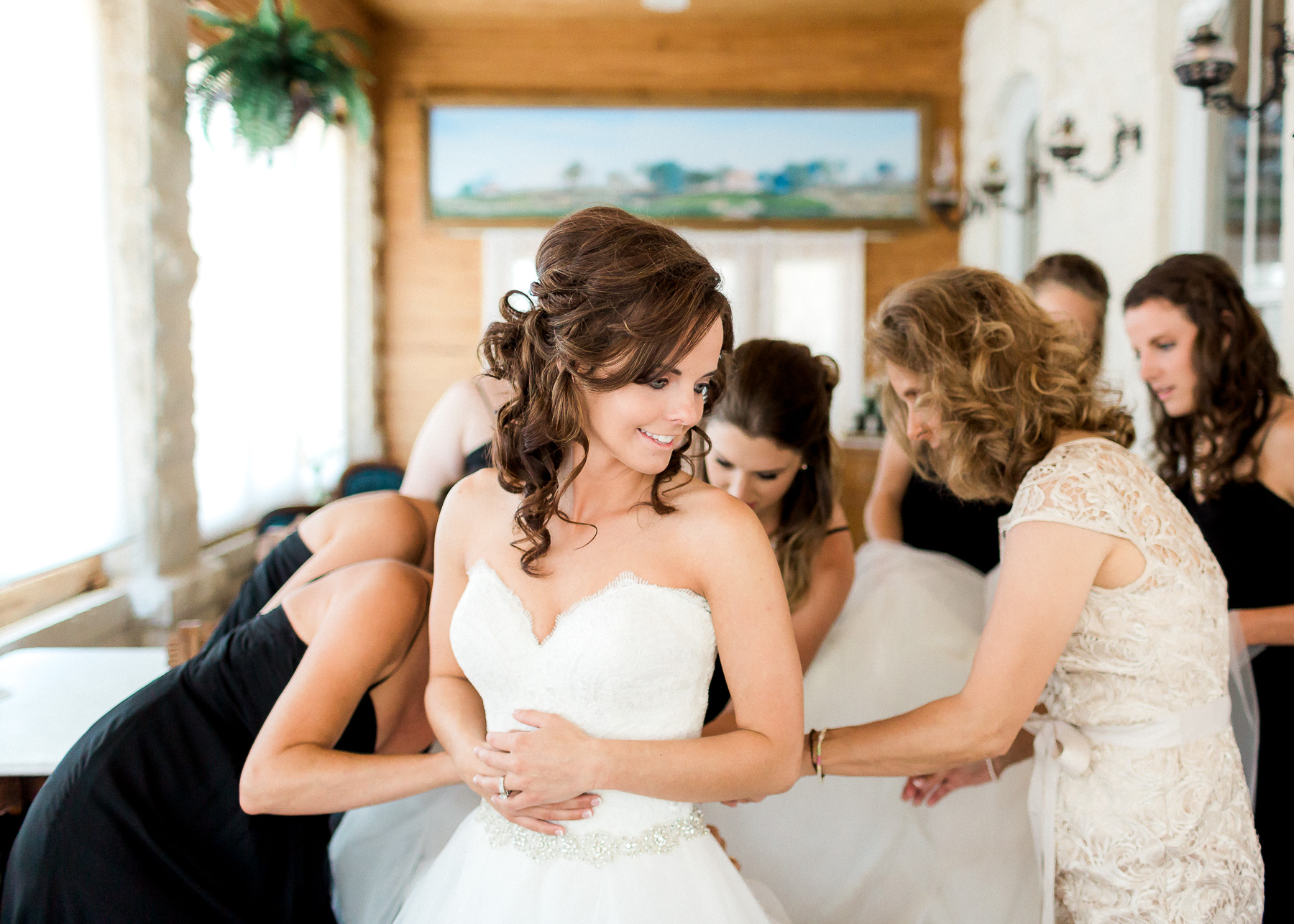 mother and sister helping button her wedding dress