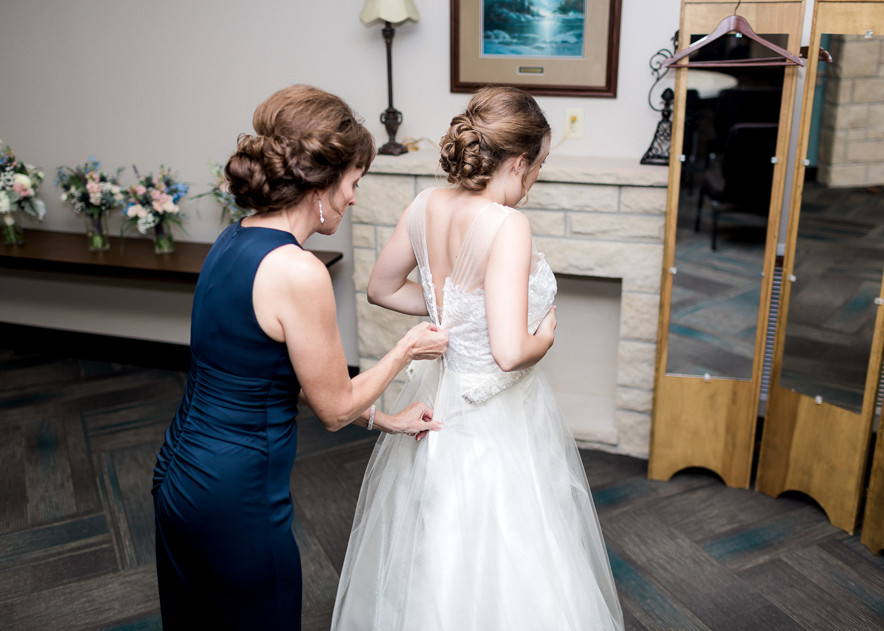 mother of bride zipping on wedding dress