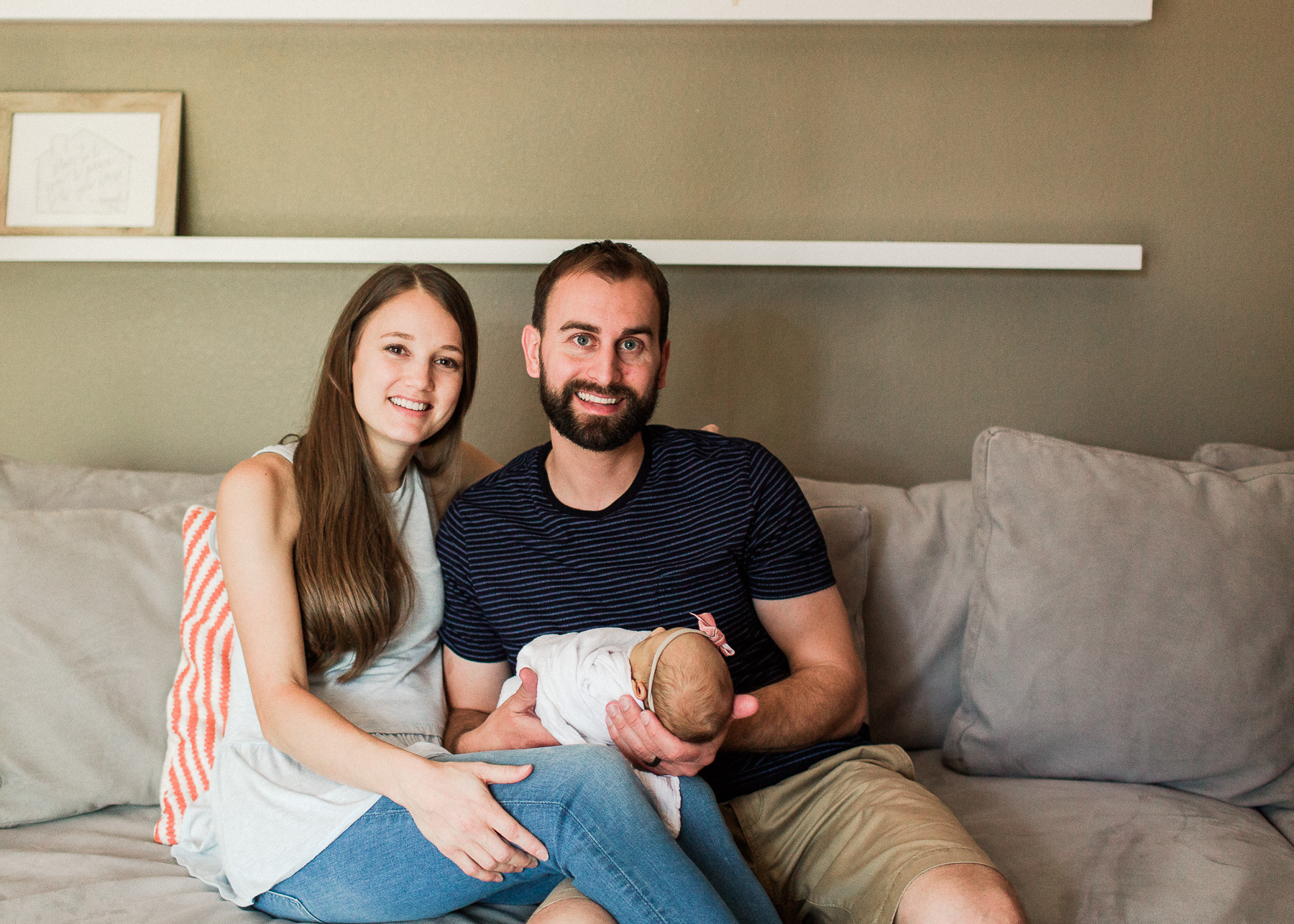parents smiling at camera while holding baby girl